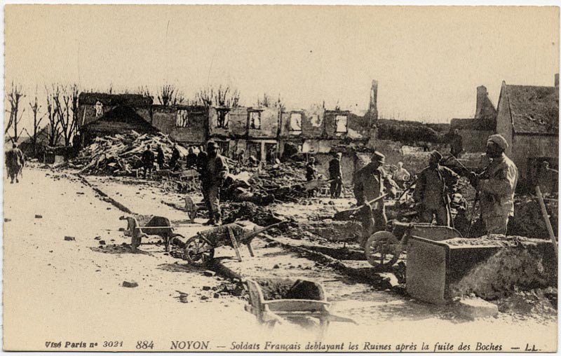Soldats français déblayant les ruines à Noyon après la fuite des allemands sur une carte postale ancienne